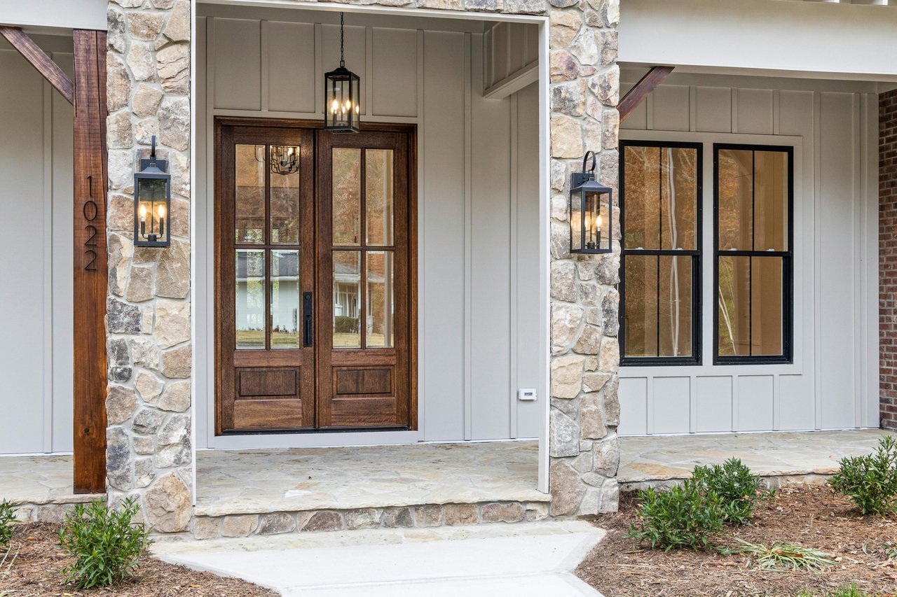 Home entrance with a dark wood double door, stone columns, and lantern lights.