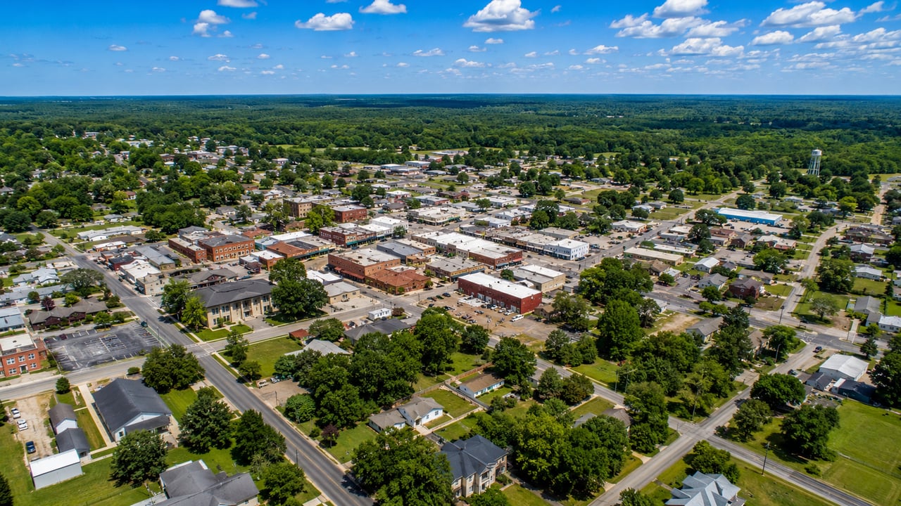 Aerial view of a small town’s downtown, surrounded by tree-lined streets and homes.