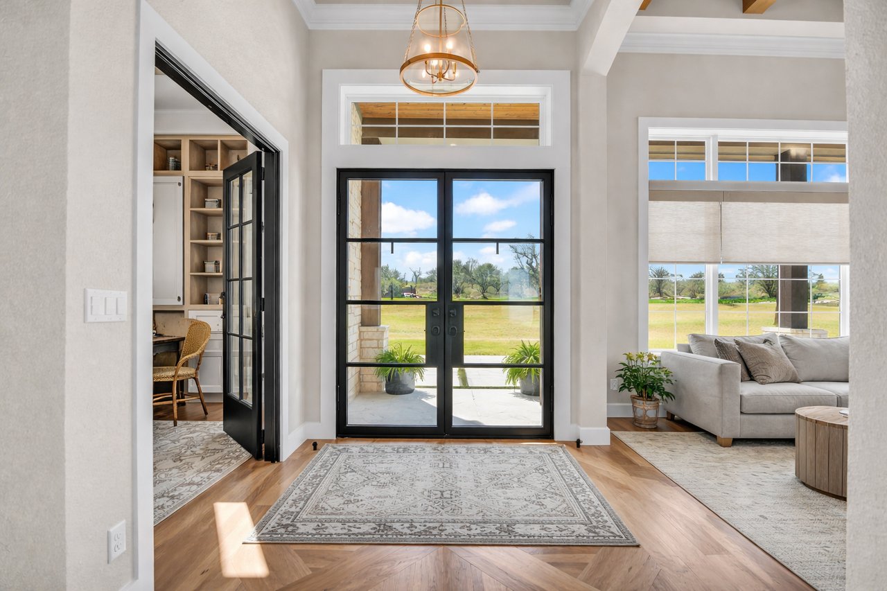 Home entryway with black-framed glass doors, a patterned rug, and views of the lawn.
